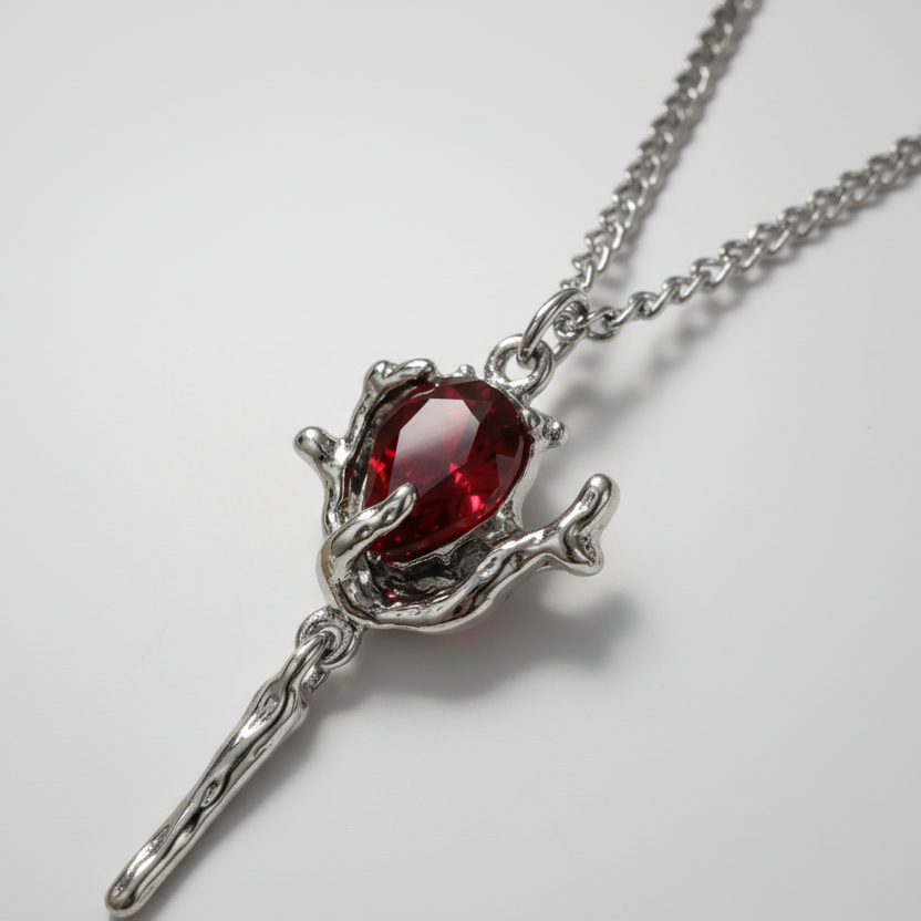 Silver necklace with a red gemstone pendant on a marble surface